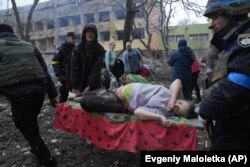 Украінскія ратавальнікі і валянтэры нясуць цяжарную жанчыну, якая пацярпела ў выніку авіяцыйнага ўдару расейскіх вайскоўцаў па радзільні і дзіцячым шпіталі ў Марыюпалі, 9 сакавіка 2022 году. Фота Яўгена Малалеткі