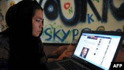 Avganistanka gleda Fejsbuk u internet kafiću u Kabulu pre nego što su talibani preuzeli vlast 2021. godine.
