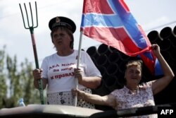 O femeie pe un tanc ține o furcă și steagul uniunii Donețkului cu Luhanskul = Novorossia, 24 august, 2014 in Donețk