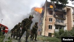 Грузинские солдаты проходят мимо дома, на который сбросил бомбу российский самолет. 9 августа, 2008