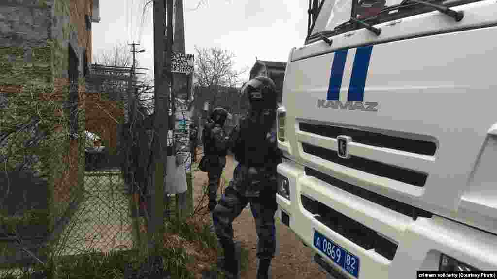 Тінту жүргізіліп жатқан үйдің жанында тұрған ресейлік күш құрылымдары қызметкерлері.