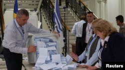 Membri ai unei comisii electorale varsă o urnă de vot după închiderea secțiilor de votare la alegerile parlamentare din Republica Moldova, la Chișinău, 28 septembrie 2025.