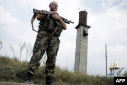 Militar ucrainean stând de pază la un punct de control lângă Donețk, astăzi 11 august.