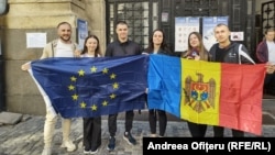 Moldavski građani u Rumuniji drže evropsku i moldavsku zastave na biračkom mestu dijaspore u Bukureštu.